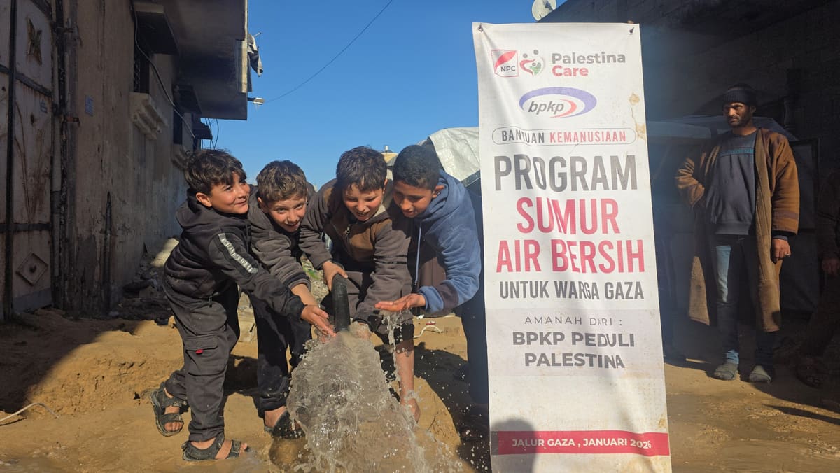 Anak-anak menikmati air dari sumur bersih di samping banner Program Sumur Air Bersih untuk warga Gaza